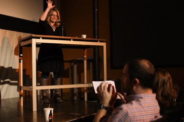 Jule Banivlle stands on stage at the festival and sets up the next group of stories. 